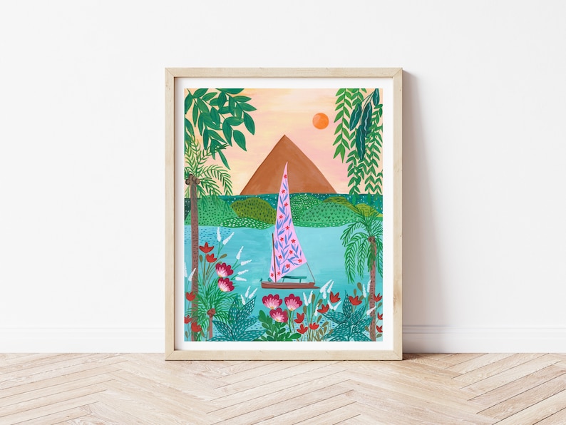 May include: A framed illustration of a sailboat with a pink and blue sail on a turquoise body of water. The sailboat is surrounded by lush green foliage and red flowers. A brown mountain is in the background with a bright orange sun in the sky.