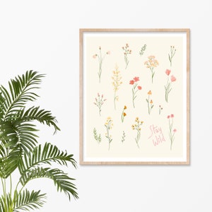 Pu&ograve; includere: Una stampa incorniciata con sfondo crema che presenta una collezione di fiori selvatici disegnati a mano in tonalit&agrave; rosa, arancio e giallo. Il testo "Stay Wild" &egrave; scritto in corsivo rosa nella parte inferiore della stampa.