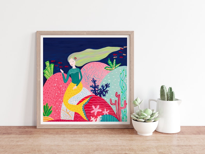 May include: A colorful illustration of a mermaid with long blonde hair sitting on a coral reef. The mermaid is wearing a green shirt and has a yellow tail. The background is a dark blue ocean with red fish swimming around.