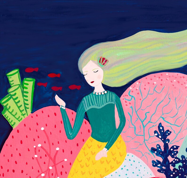 May include: A mermaid with long blonde hair sits on a pink coral reef. She is wearing a green shirt and a yellow skirt with a white and blue pattern. There are red fish swimming around her.