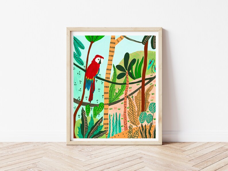 May include: A framed art print featuring a vibrant illustration of a red, blue, and yellow macaw perched on a branch in a lush jungle setting. The artwork includes various green plants, trees, and a light blue sky.
