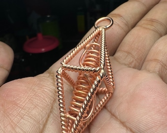 May include: A copper wire cage pendant with a spiral inside. The cage is in the shape of a pyramid with a rounded top.