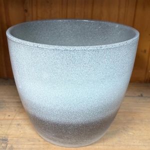 May include: A gray and white ombre planter with a speckled finish. The planter is round and has a wide opening.