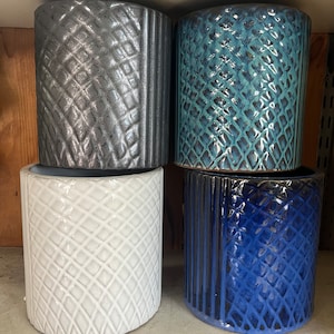 May include: Four ceramic planters with different geometric patterns. The planters are in shades of gray, blue, white, and dark blue.