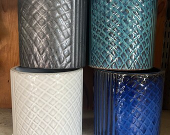 May include: Four ceramic planters with different geometric patterns. The planters are in shades of gray, blue, white, and dark blue.