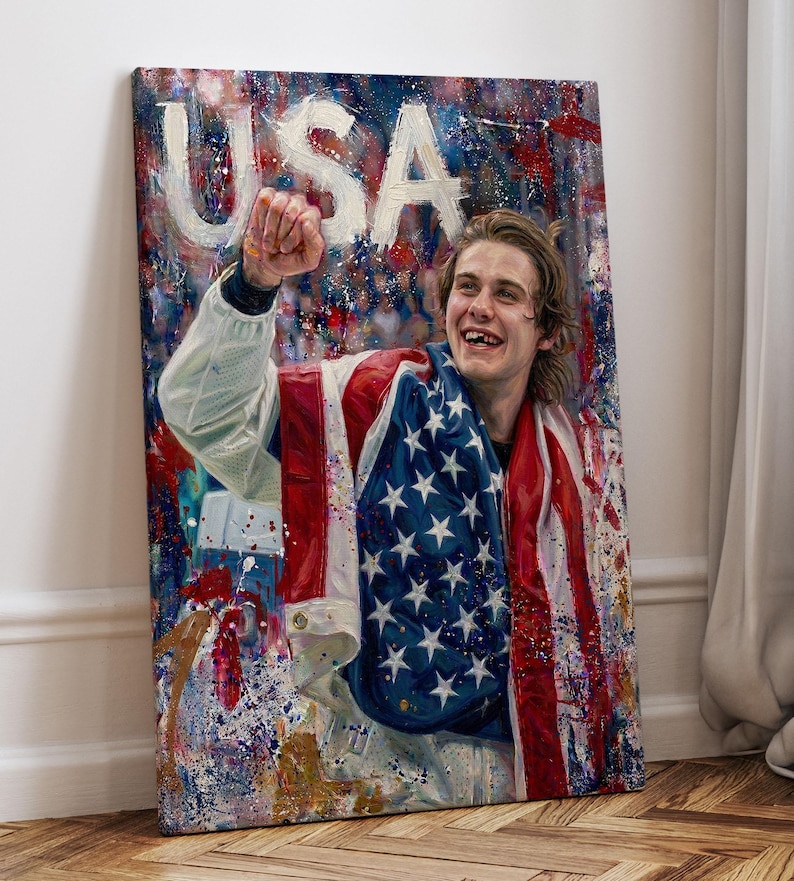 Pode incluir: Impress&atilde;o em tela com um retrato de uma pessoa sorrindo envolta em uma bandeira americana. A palavra "USA" est&aacute; pintada em letras brancas grandes no topo. A obra de arte tem um fundo colorido e abstrato com respingos de tinta.