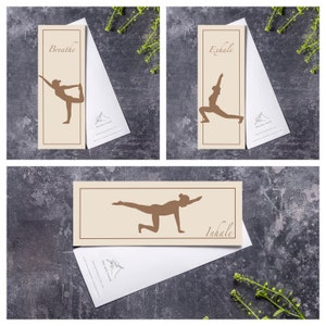 May include: Three yoga-themed bookmarks with white envelopes. Each bookmark features a brown silhouette of a yoga pose against a beige background, with the words "Breathe," "Exhale," and "Inhale" printed on them. The envelopes have a hand-drawn logo.