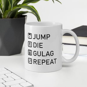 May include: White ceramic coffee mug with black text that reads "JUMP DIE GULAG REPEAT".