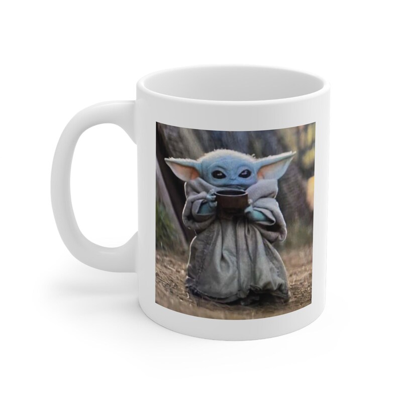Puede incluir: Taza de cer&aacute;mica blanca con una imagen colorida de un personaje ficticio sosteniendo una taza. El personaje lleva una t&uacute;nica marr&oacute;n y tiene orejas grandes. El fondo es una escena de bosque borrosa.