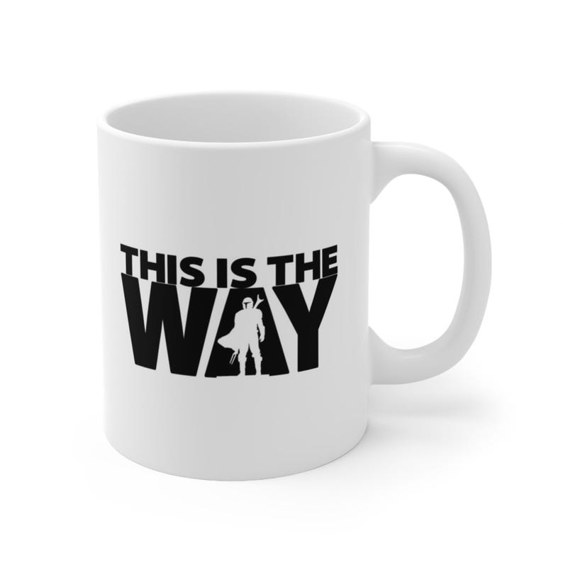 May include: White ceramic coffee mug with a black silhouette of a Mandalorian character and the text "This is the Way".
