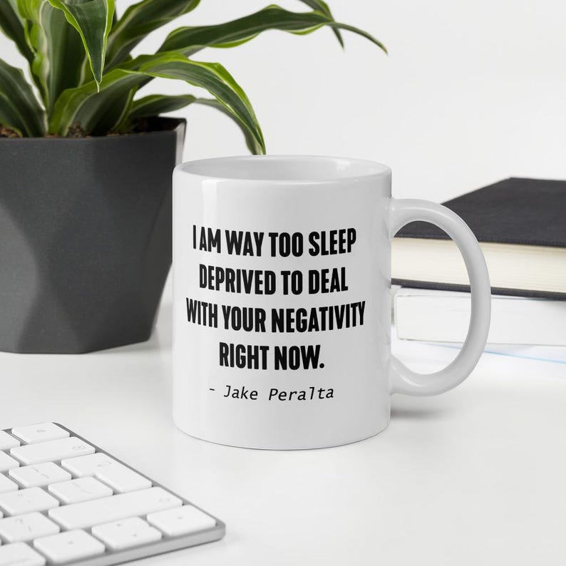 May include: White ceramic coffee mug with black text that reads "I am way too sleep deprived to deal with your negativity right now. - Jake Peralta"