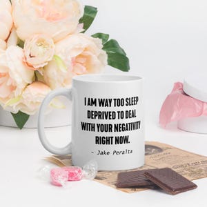 May include: White ceramic coffee mug with a black quote that reads "I am way too sleep deprived to deal with your negativity right now. - Jake Peralta".