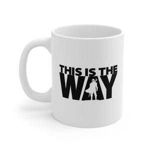 May include: White ceramic coffee mug with a black silhouette of a Mandalorian character and the text "This is the Way".