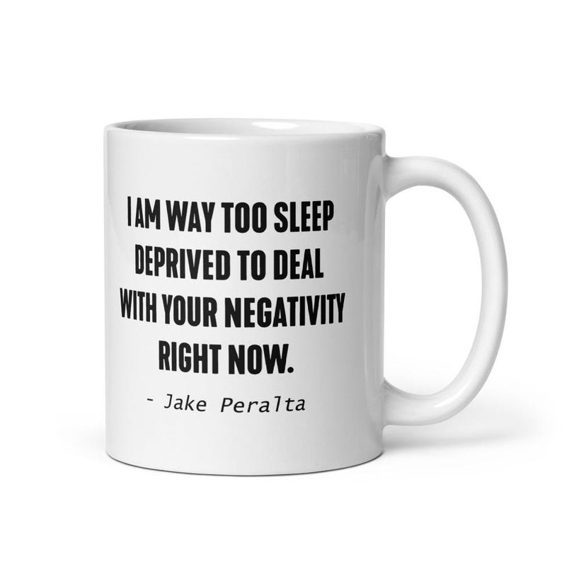 May include: White ceramic coffee mug with black text that reads "I am way too sleep deprived to deal with your negativity right now. - Jake Peralta"