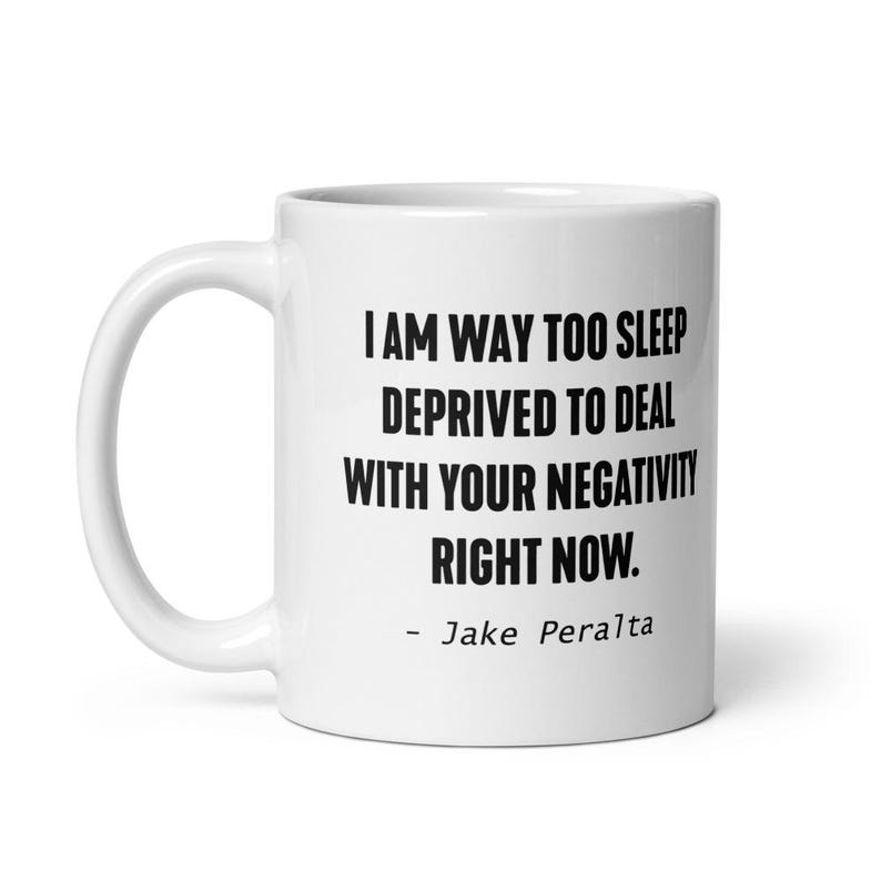 May include: White ceramic coffee mug with black text that reads "I am way too sleep deprived to deal with your negativity right now. - Jake Peralta"