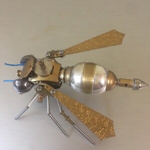 May include: A gold and silver steampunk-style wasp sculpture with intricate details and a textured finish.