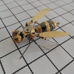 May include: A detailed steampunk-style metal wasp sculpture with gold and black accents. The wasp has intricate gears and moving parts, and its wings are spread wide.