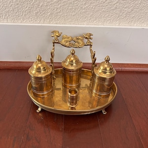 May include: A set of three ceramic mugs with a speckled, cream-colored glaze. Each mug features a different hand-painted floral design in shades of blue, green, and yellow. The mugs have a simple, modern shape.