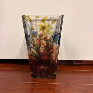 Pu&ograve; includere: Un vaso di vetro trasparente di forma rettangolare e con la parte superiore svasata. Il vaso &egrave; decorato con un colorato motivo floreale con fiori gialli, rossi e blu. Il vaso &egrave; alto circa 20 cm.