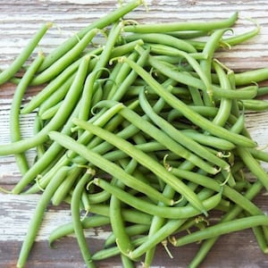 May include: A bunch of fresh green string beans on a rustic wooden surface.