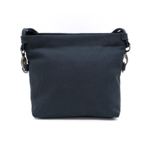 May include: A dark grey canvas crossbody bag with silver hardware and a simple design.