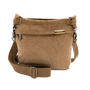 Op de afbeelding: Een bruin corduroy crossbodytasje met een lange verstelbare riem en zilverkleurige hardware. De tas heeft een rechthoekige vorm met een overslag en een klein label met de tekst "seasara".