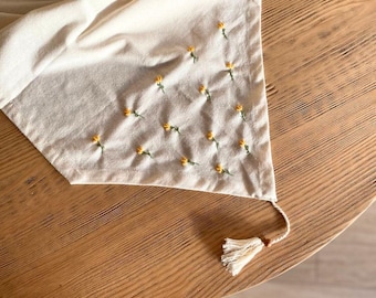 Tovaglia minimalista in lino con delicato ricamo floreale.