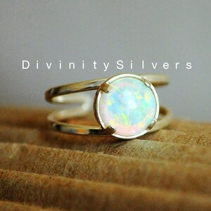 May include: A silver ring with a white opal gemstone. The ring has a double band design.