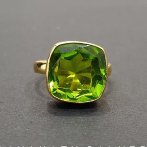 Puede incluir: Un anillo de oro con una gran piedra preciosa verde cuadrada.