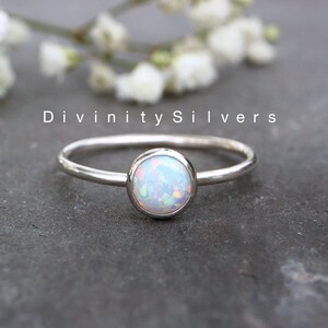 May include: A silver ring with a white opal gemstone. The ring is simple and elegant, perfect for everyday wear.