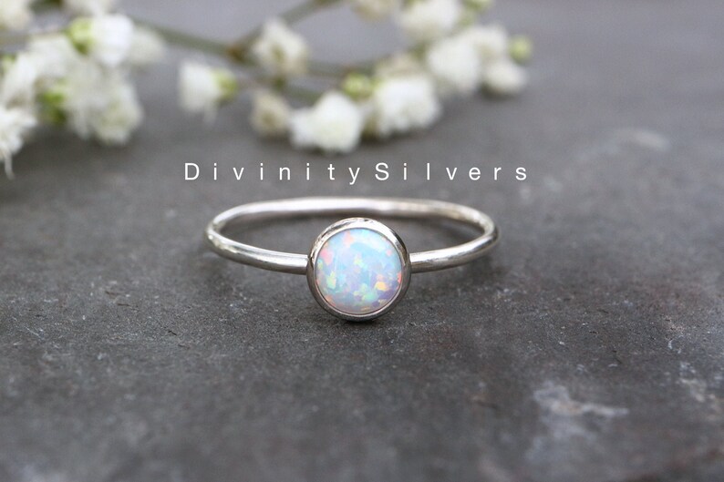 May include: A silver ring with a white opal gemstone. The ring is simple and elegant, perfect for everyday wear.