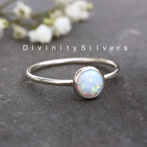 May include: A delicate silver ring with a white opal gemstone. The ring is simple and elegant, perfect for everyday wear.
