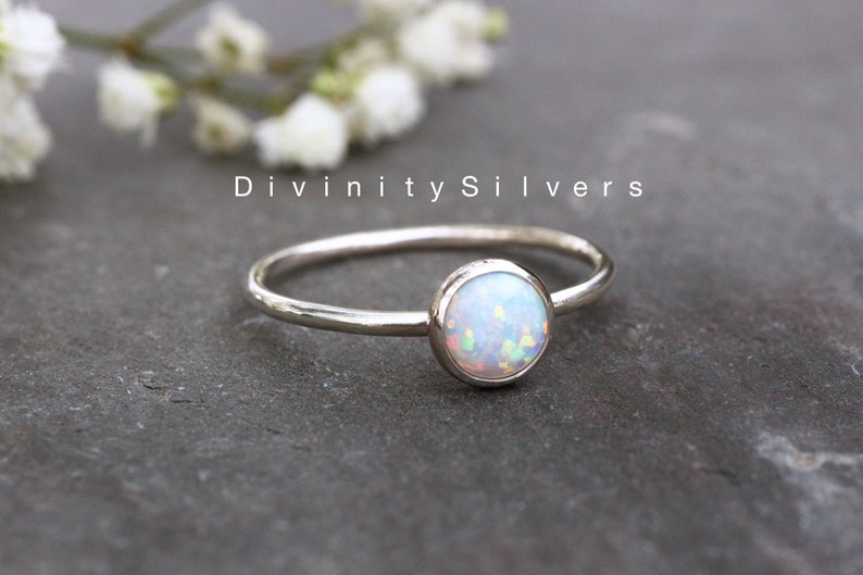 May include: A delicate silver ring with a white opal gemstone. The ring is simple and elegant, perfect for everyday wear.