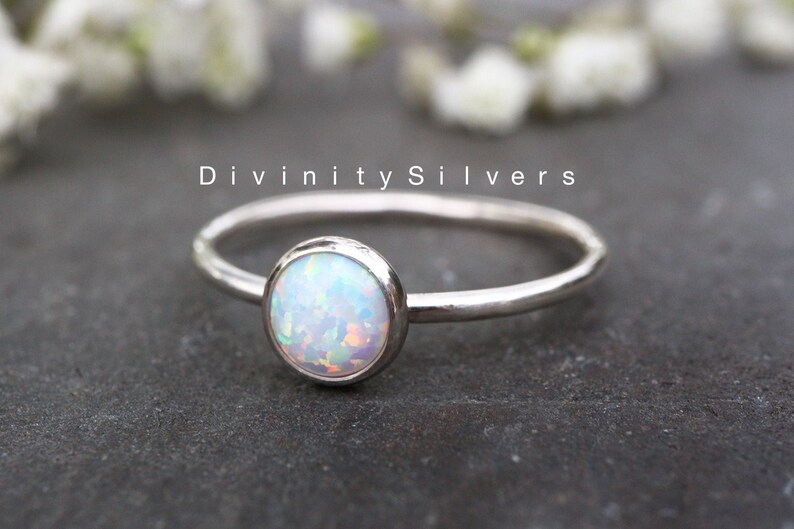 May include: A delicate silver ring with a white opal gemstone. The ring is simple and elegant, perfect for everyday wear.
