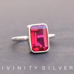 Peut inclure: Une bague en argent avec une grande pierre pr&eacute;cieuse rectangulaire rouge fonc&eacute;.