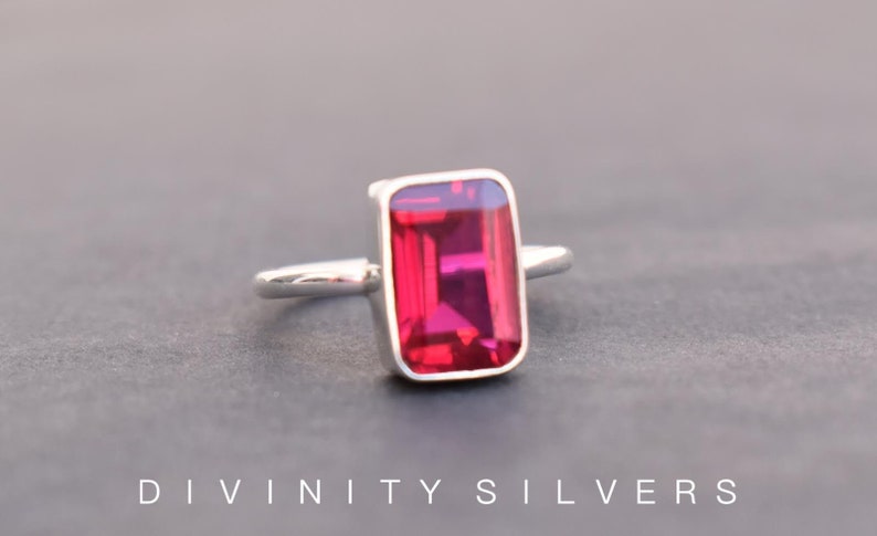Peut inclure: Une bague en argent avec une grande pierre pr&eacute;cieuse rectangulaire rouge fonc&eacute;.