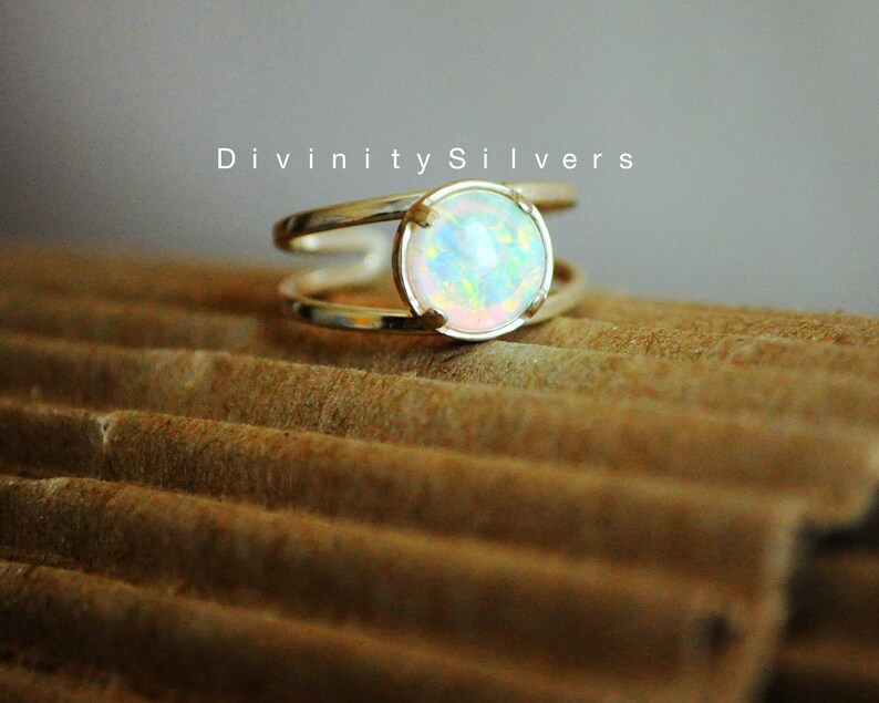 May include: A silver ring with a white opal gemstone. The ring has a double band design.