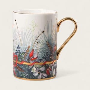 May include: White ceramic mug with a gold handle and rim. The mug features a botanical design with green, red, and gold accents. A red ribbon and gold band wrap around the base of the mug, adding a festive touch.