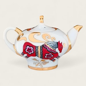 Könnte beinhalten: Weiße Porzellan-Teekanne mit einem roten und goldenen Design eines stilisierten Tieres. Die Teekanne hat einen runden Körper und einen Ausguss an der Seite.