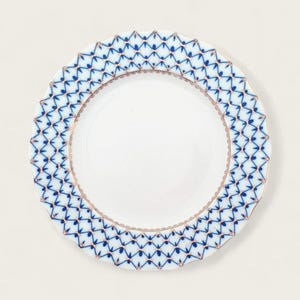 May include: A white porcelain plate with a blue and gold geometric pattern around the edge.
