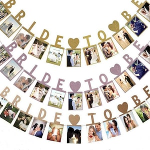 Puede incluir: Una pancarta de despedida de soltera rosa y dorada con las palabras "Bride to Be" y corazones. La pancarta está decorada con fotos de parejas.