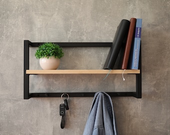 May include: A black metal shelf with a wooden top shelf and hooks underneath. A potted plant sits on the top shelf, and a stack of books and a jacket hang on the hooks.