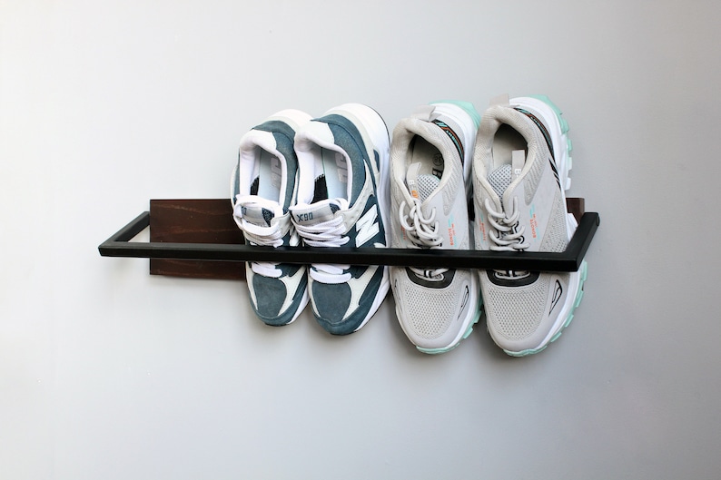 May include: A black metal shoe rack with a wooden shelf, holding four pairs of sneakers. Two pairs are blue and white, and two pairs are gray and white.