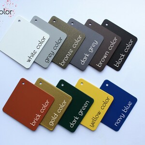 May include: A set of 12 small square samples of different colors, including white, grey, bronze, dark grey, brown, black, brick, gold, dark green, yellow, and navy blue. Each sample has the color name written on it in white text.