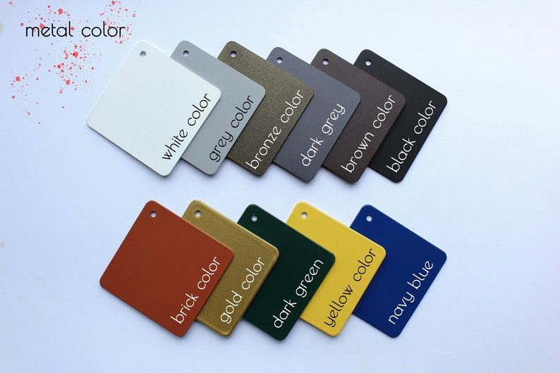 May include: A set of 12 small square samples of different colors, including white, grey, bronze, dark grey, brown, black, brick, gold, dark green, yellow, and navy blue. Each sample has the color name written on it in white text.