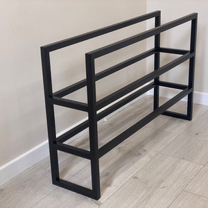 May include: Black metal shoe rack with four shelves. The rack is made of sturdy metal and has a simple, modern design.