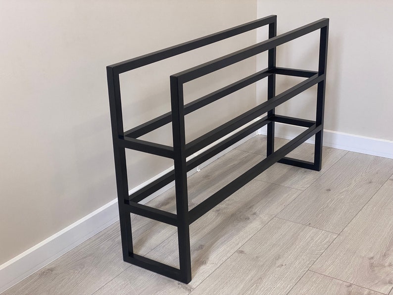 May include: Black metal shoe rack with four shelves. The rack is made of sturdy metal and has a simple, modern design.