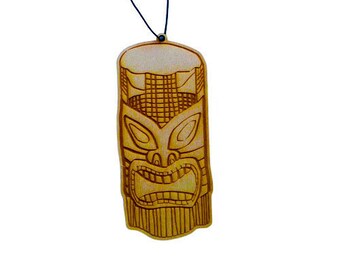 May include: A wooden tiki idol with a carved face and a string for hanging. The idol is brown and has a detailed design.