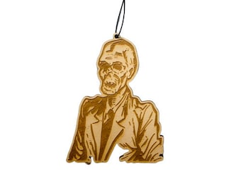 May include: A wooden ornament of a skeleton wearing a suit. The ornament is hanging from a black string.