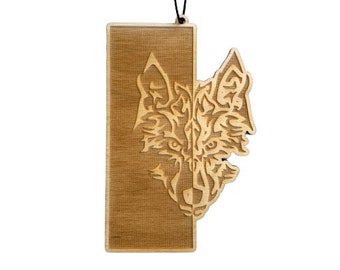 May include: A wooden ornament featuring a detailed wolf head design. The wolf's face is partially hidden behind a rectangular wooden panel. The ornament is suspended by a black string.
